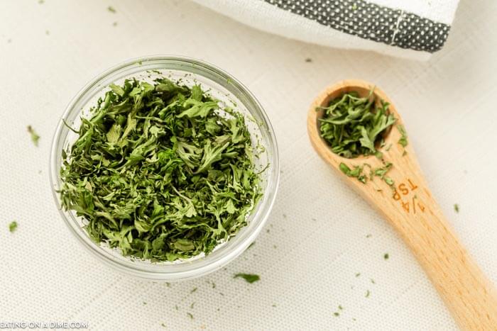 Close up image of dried parsley in a bowl with a ¼ teaspoon of dried parsley.