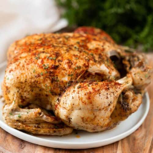 Roasted whole chicken plated on a silver platter.