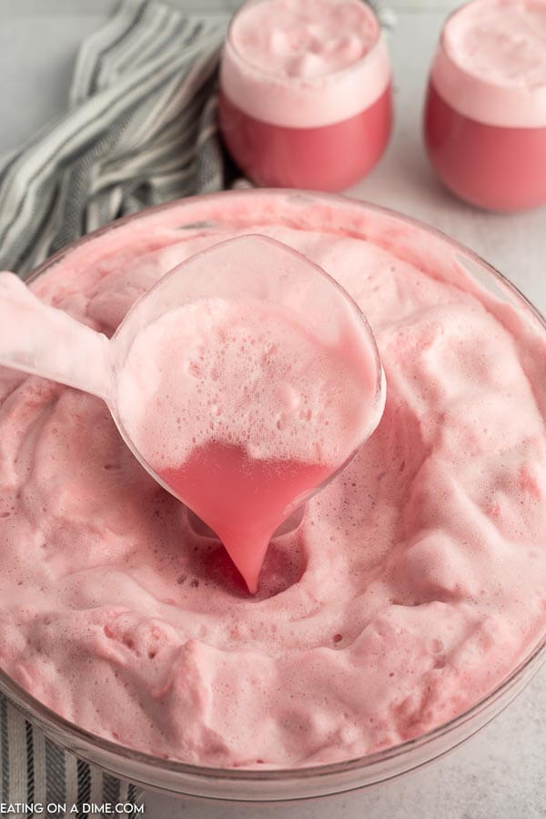 Close up image raspberry sherbet punch in a punch bowl with a serving on a ladle. 
