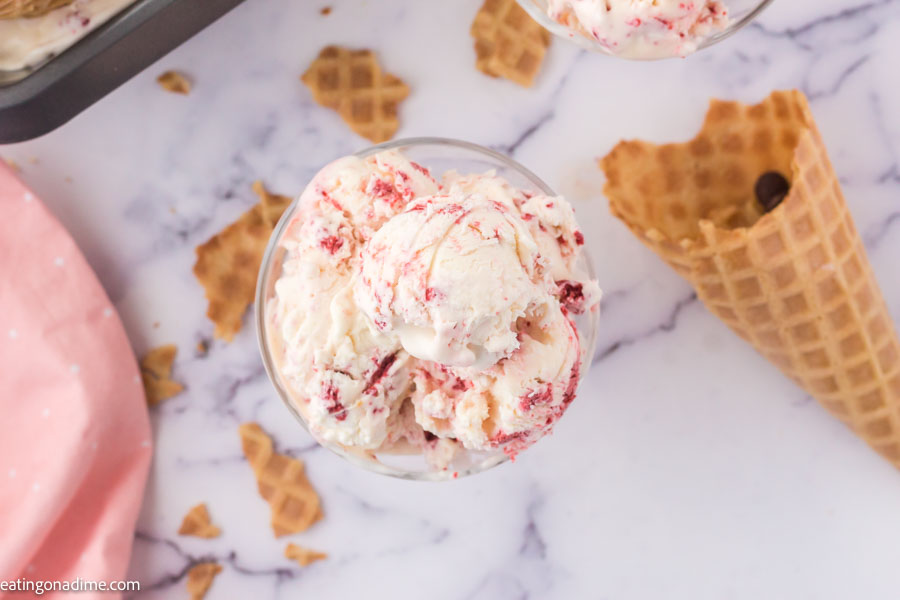 Close up image of red velvet ice cream in a serving dish with waffle cone on the side