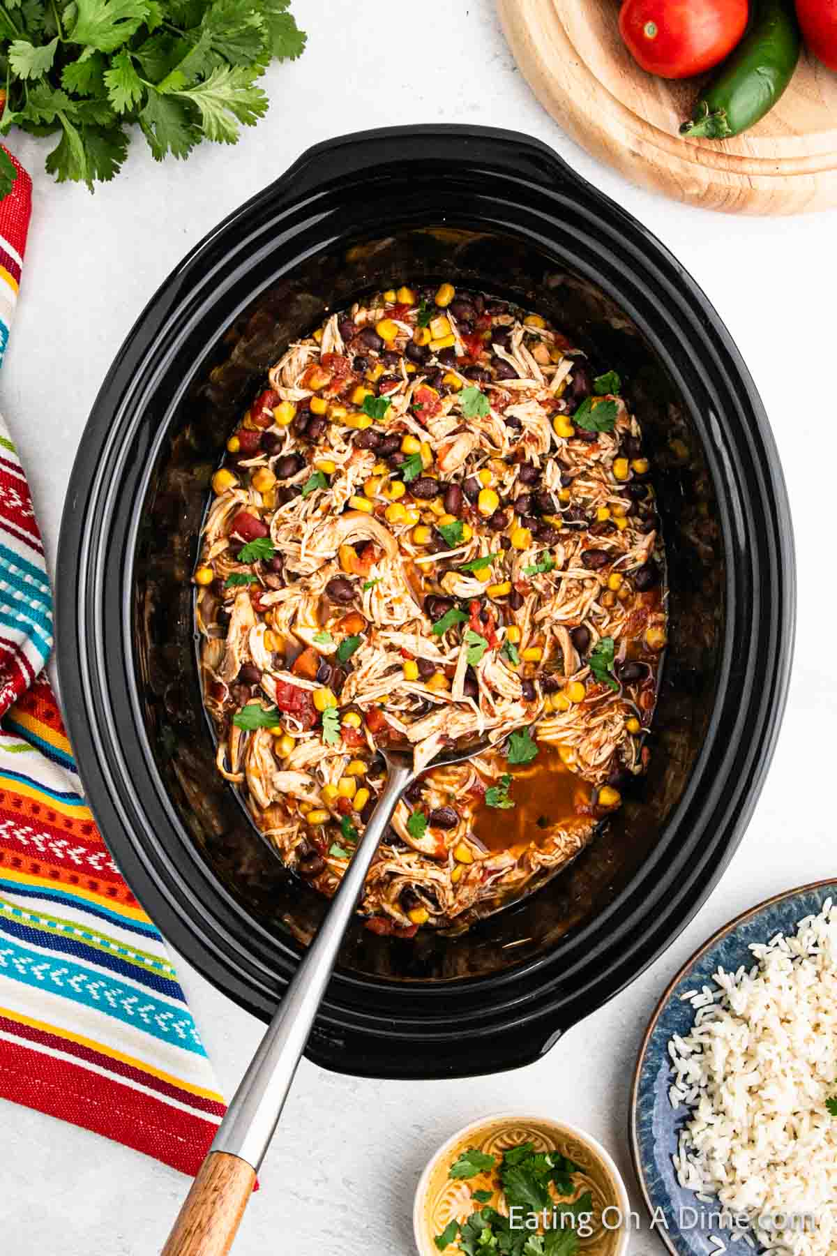 Shredded cooked chicken mixed with corn, black beans and diced tomatoes topped with fresh cilantro in the crock pot