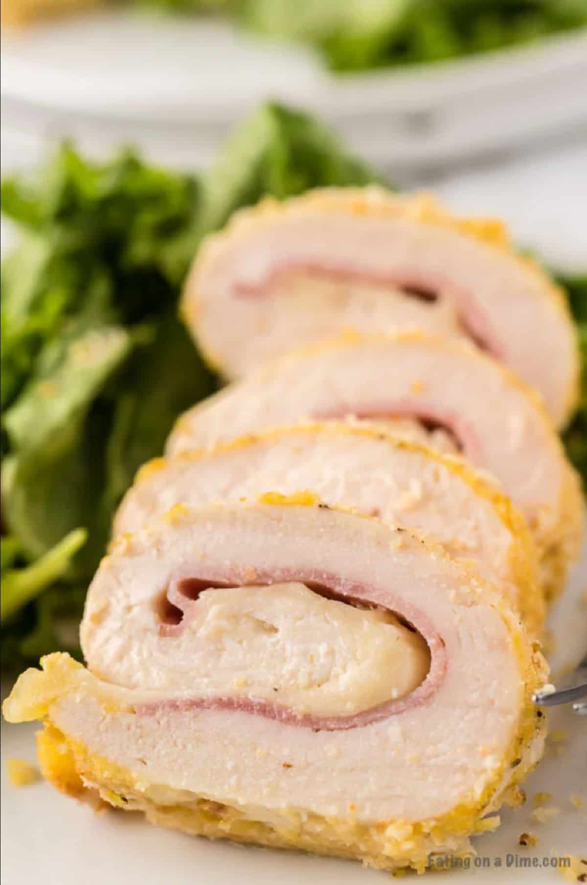 Close up image of chicken on a white plate with a side salad.
