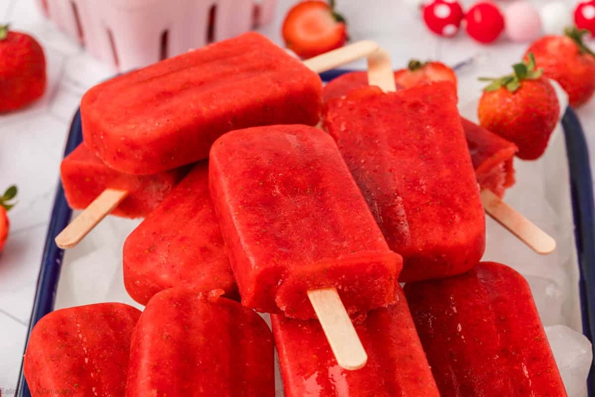Strawberry Popsicles stacked on a large pan of ice cubes