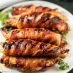Bacon wrapped chicken on a plate with parsley.