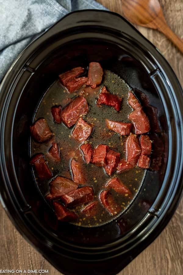 Close up image of beef in the crock with the sauce just poured over it. 