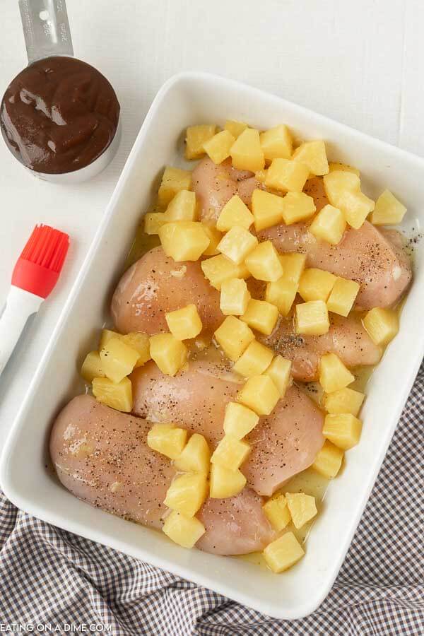 Chicken in a baking dish with pineapple on top. 