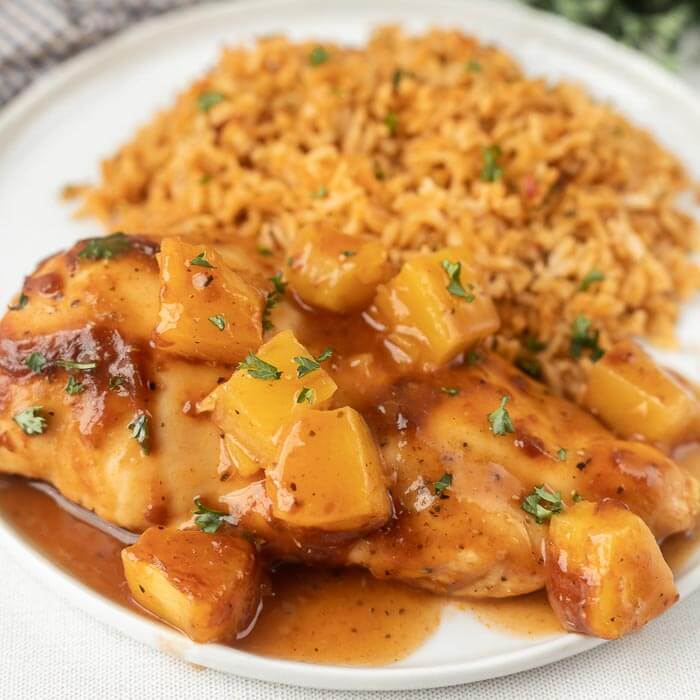 Close up image of BBQ Pineapple chicken on a plate with a side of rice. 