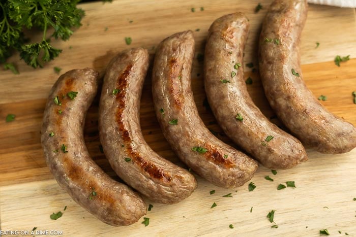 Close up image of cooked brats on a cutting board. 