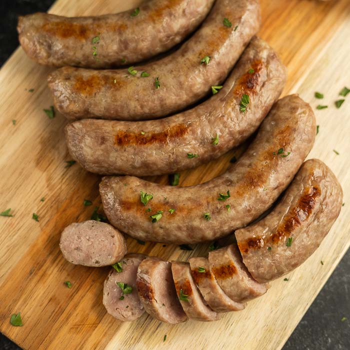 Close up image of cooked brats on a cutting board. 