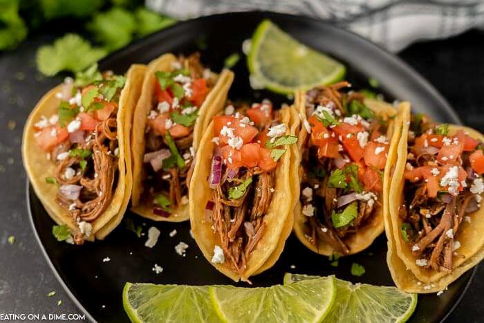 Close up image of street tacos on a plate with a side of limes. 