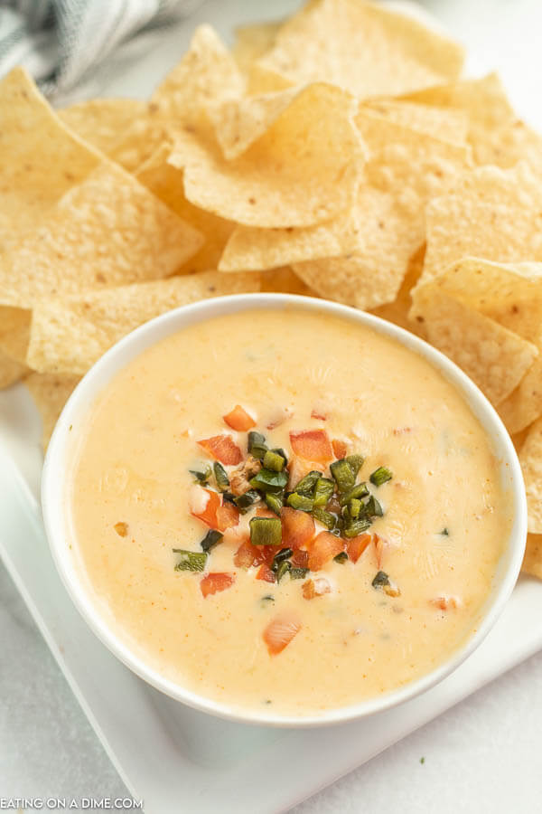 Close up image of Qdoba Queso and a white bowl with a side of chips. 