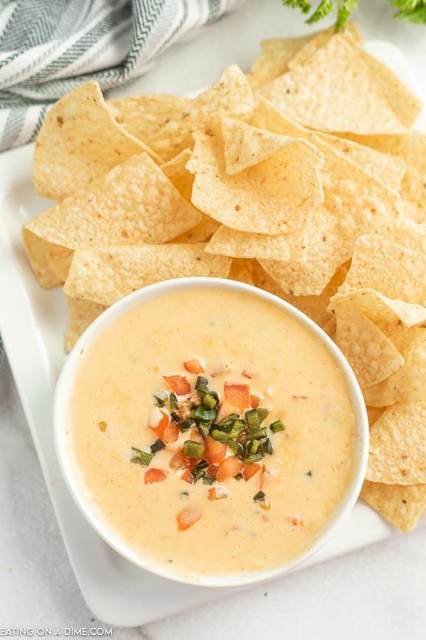 Close up image of Qdoba Queso and a white bowl with a side of chips. 
