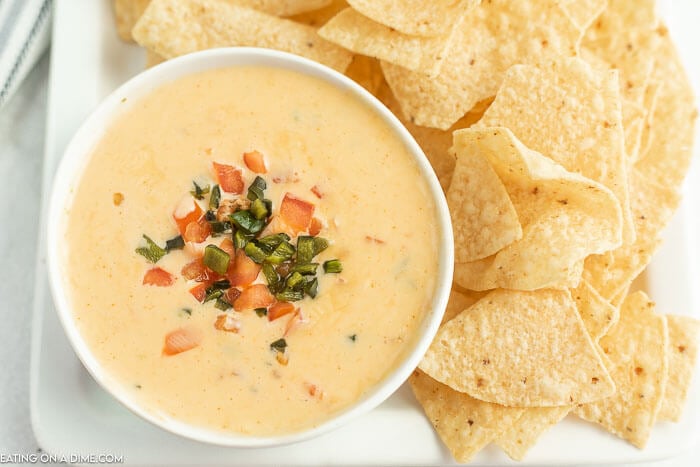 Close up image of Qdoba Queso and a white bowl with a side of chips. 
