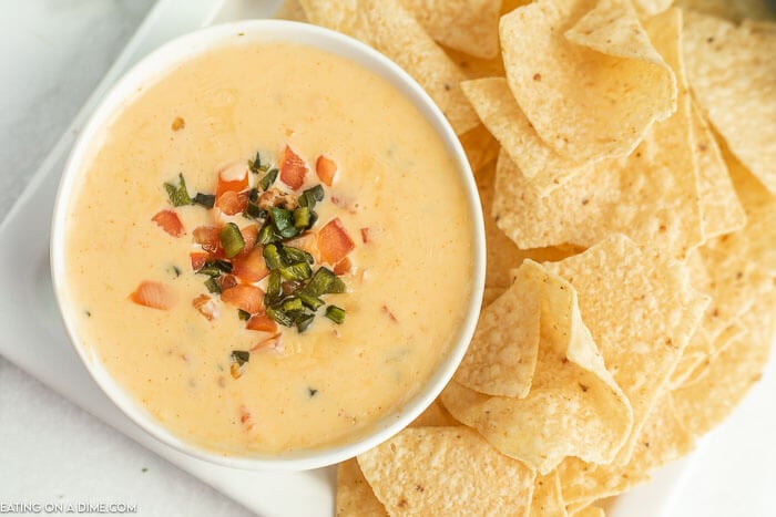 Close up image of Qdoba Queso and a white bowl with a side of chips. 