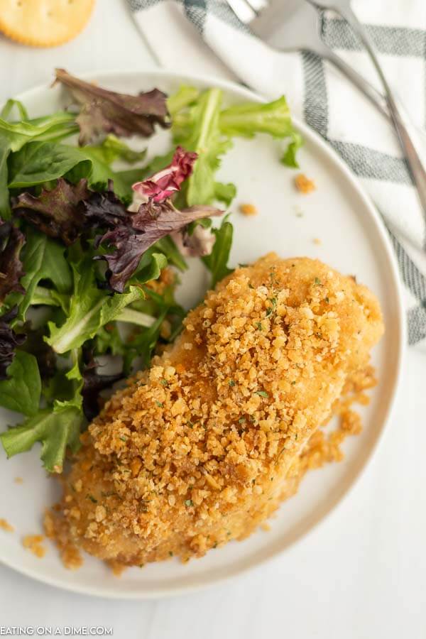 Close up image of ritz cracker chicken with a side salad on a white plate. 