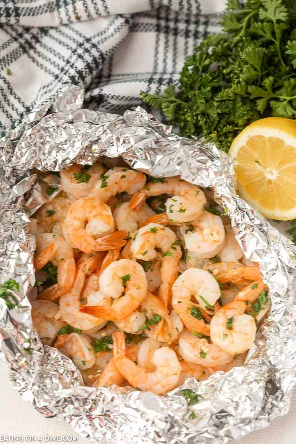 Grilled shrimp foil packet beside a lemon. 