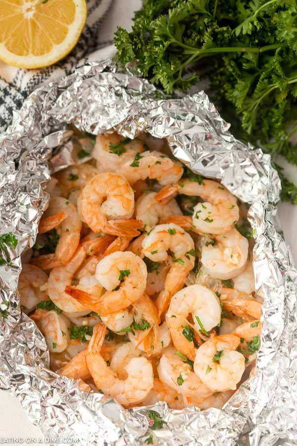 Grilled shrimp foil packet beside a lemon. 