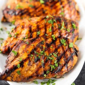 Grilled Balsamic glazed chicken stacked on a platter.