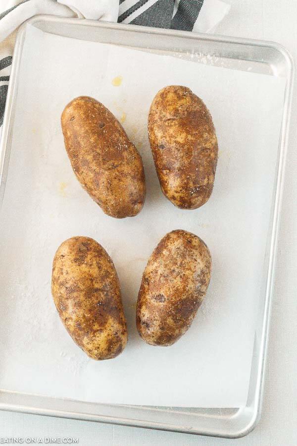 4 potatoes on a parchment paper lined baking pan. 