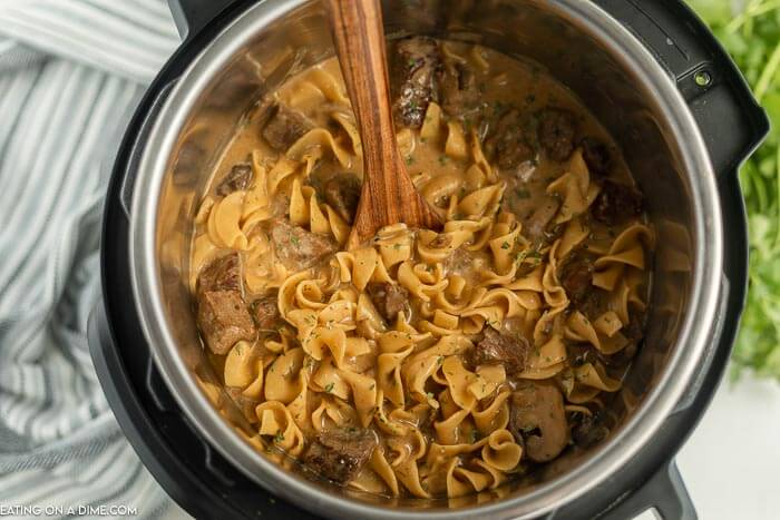 beef stroganoff in an instant pot with a wooden spoon