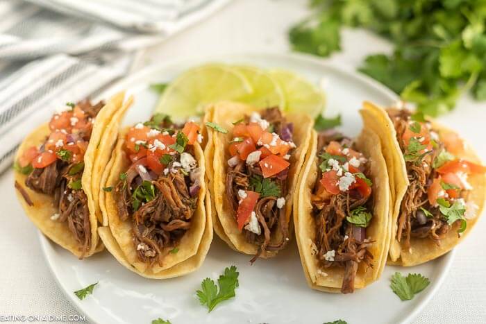 Close up image of carne asada tacos on a white plate. 