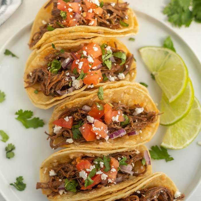 Close up image of carne asada tacos on a white plate. 