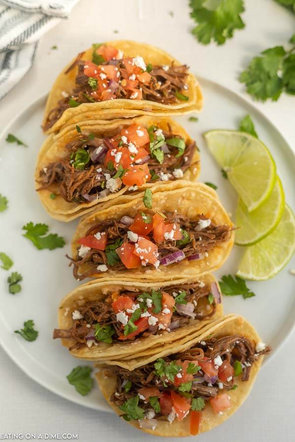 Close up image of carne asada tacos on a white plate. 