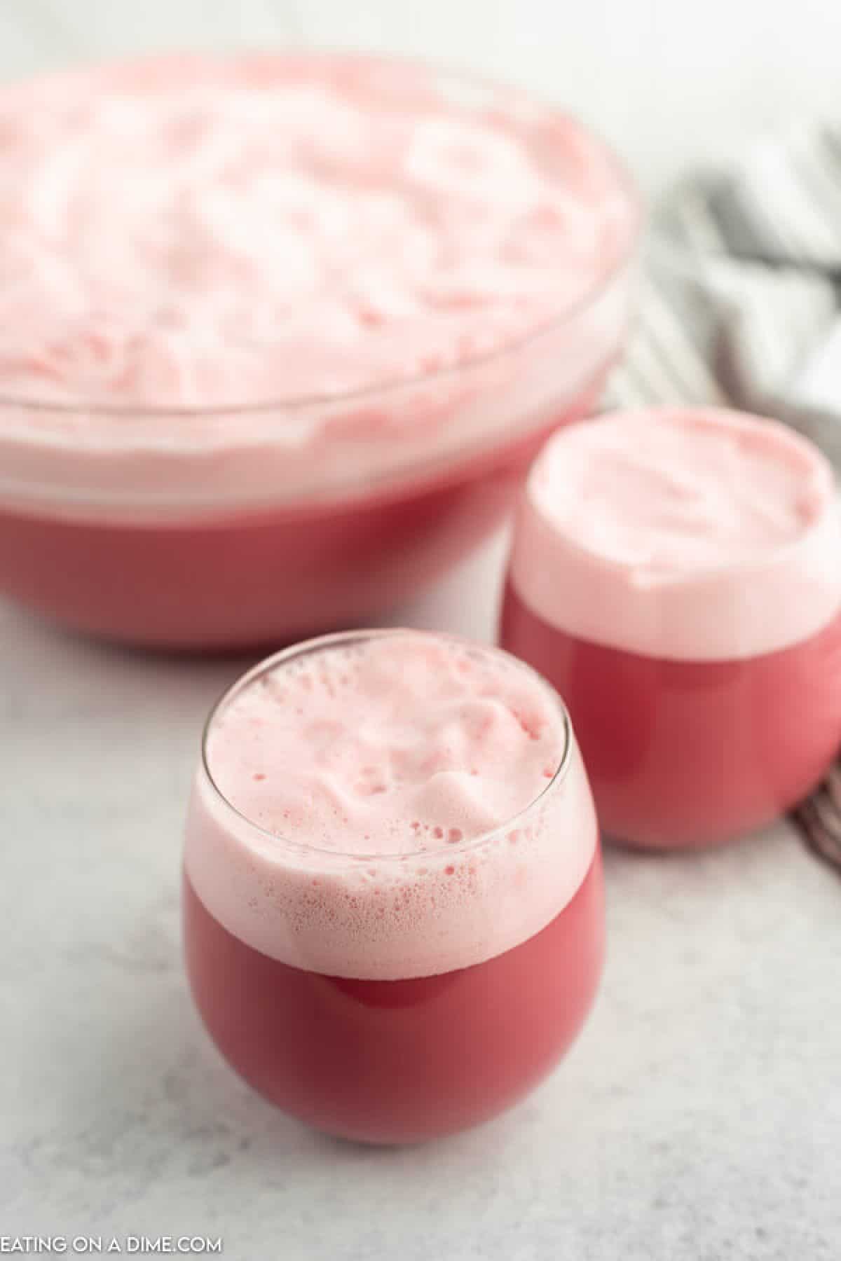 Close up image raspberry sherbet in two glasses and in a punch bowl.