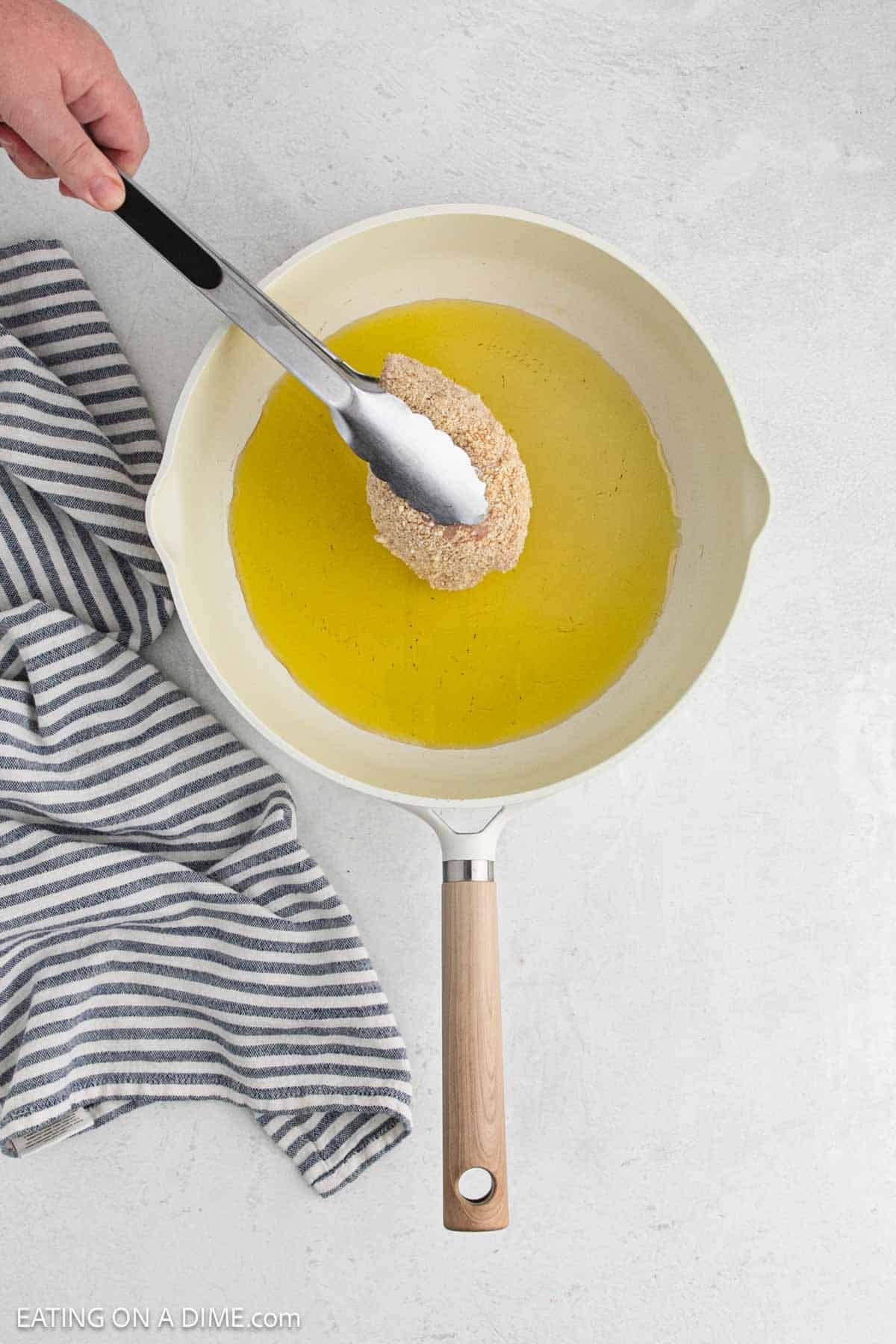 Placing the breaded chicken cutlets in a skillet with oil.