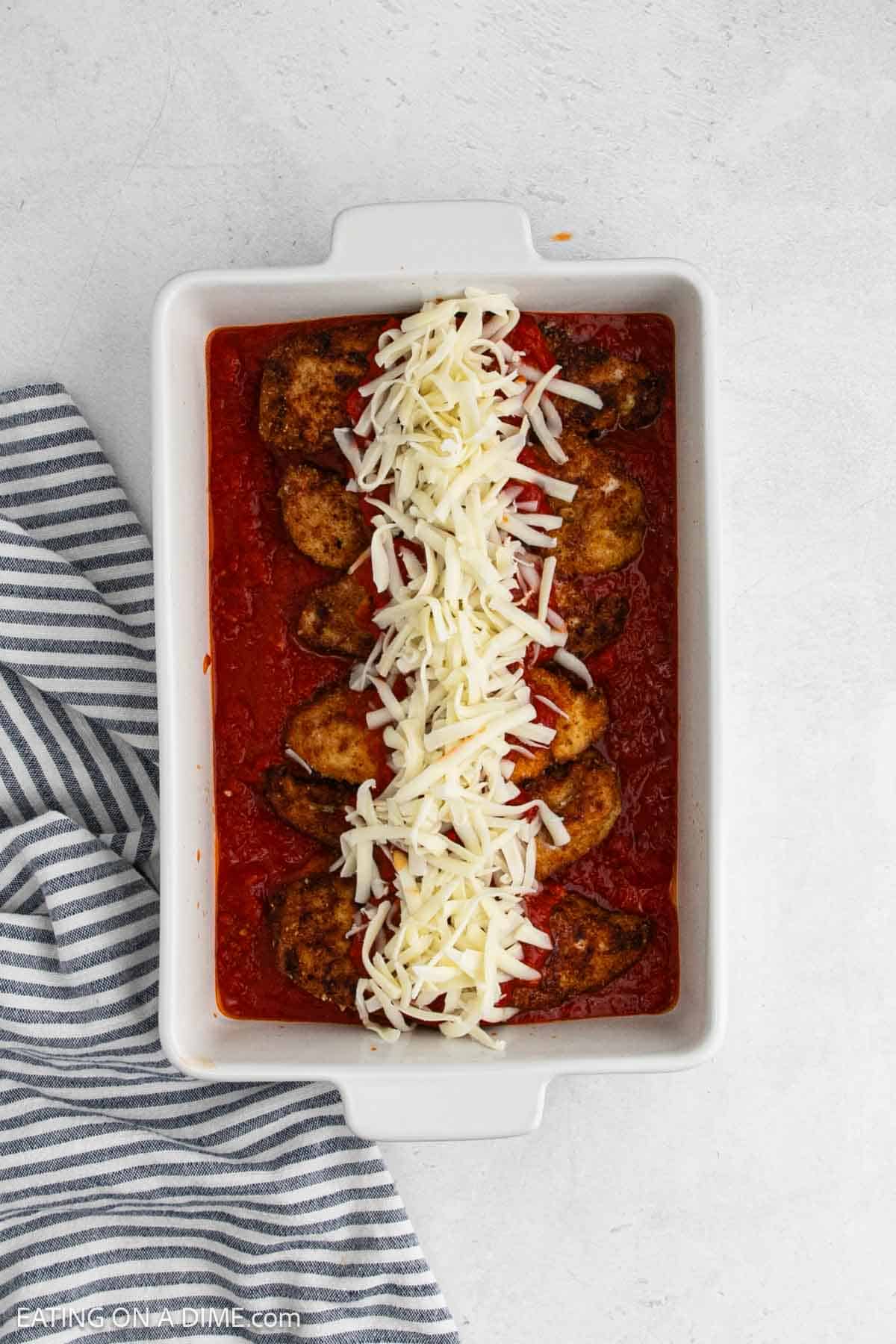 Fry chicken in a baking dish over marinara sauce topped with shredded mozzarella cheese.
