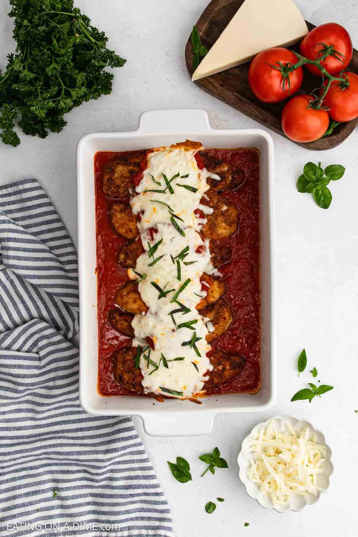 Crispy chicken in a baking dish over marinara sauce topped with melted cheese.