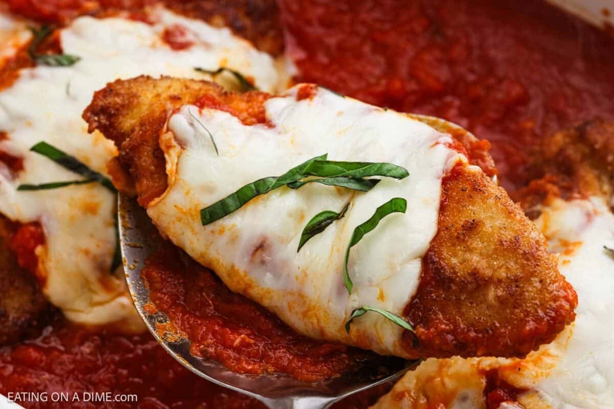 Chicken parmesan in a baking dish with a serving on a spatula.