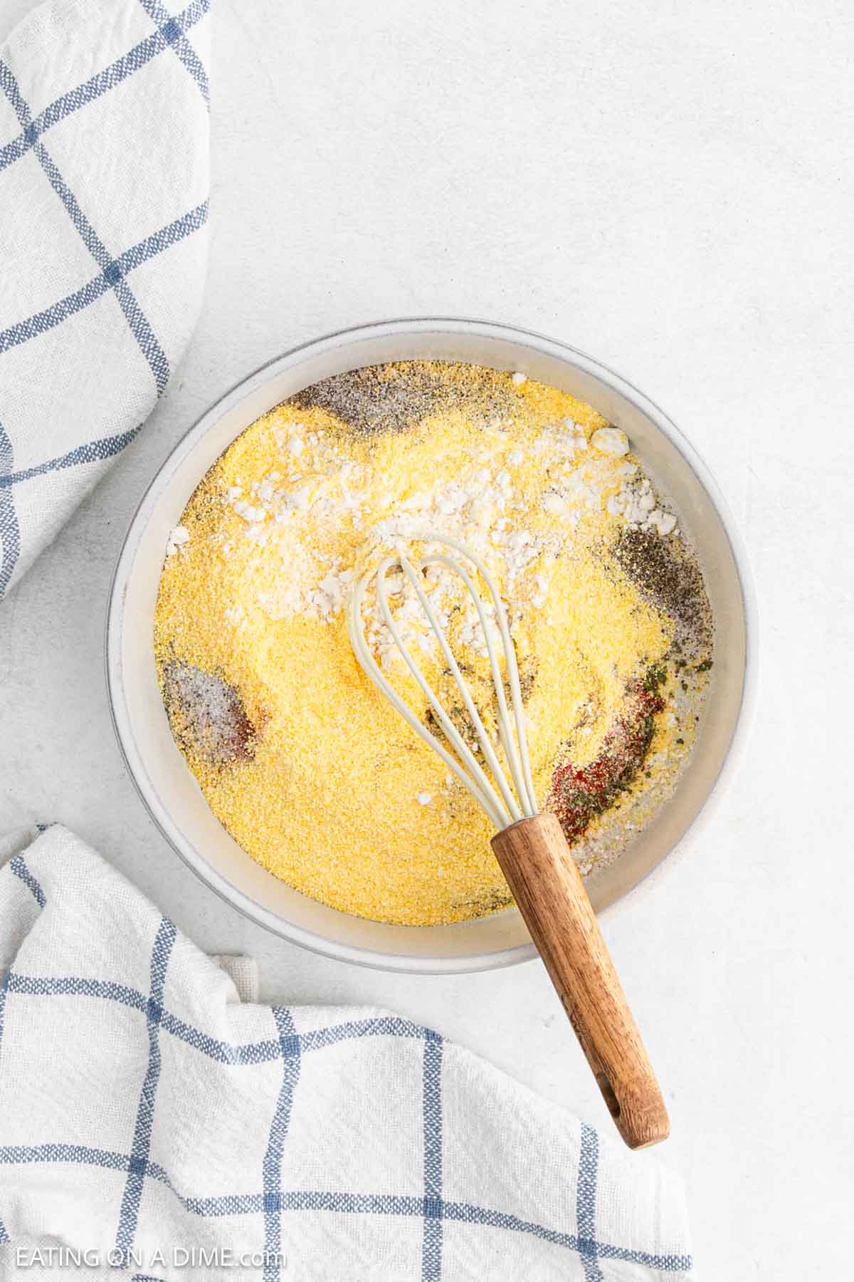 flour, cornmeal and seasonings in a bowl with a whisk
