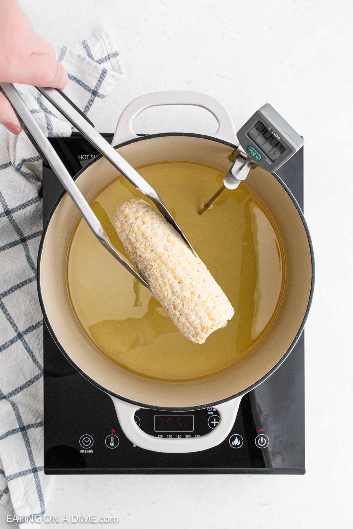 Placing the seasoned corn on the cob in the hot oil deep fryer