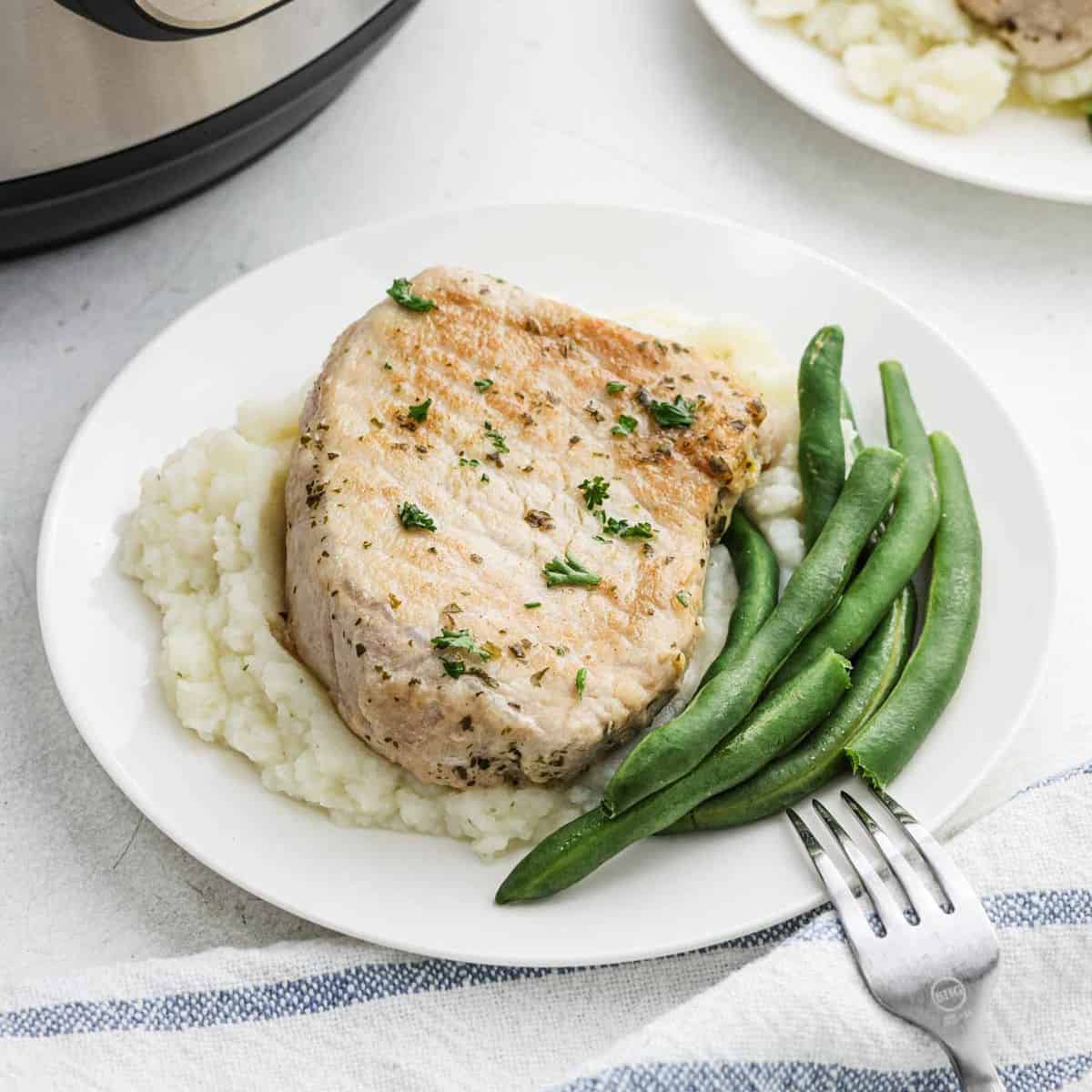 Pork Chops on a plate with a side of green beans.