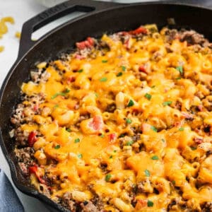 Sausage Macaroni and cheese in a cast iron skillet with melted cheese on top.