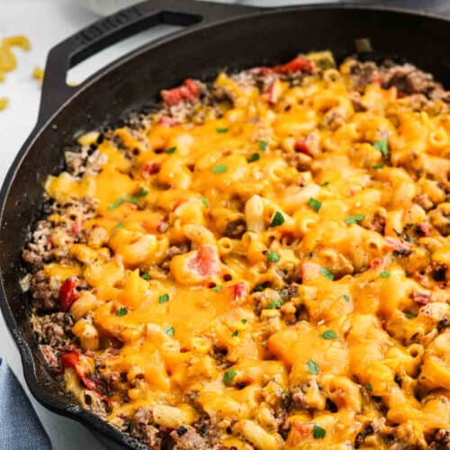 Sausage Macaroni and cheese in a cast iron skillet with melted cheese on top.