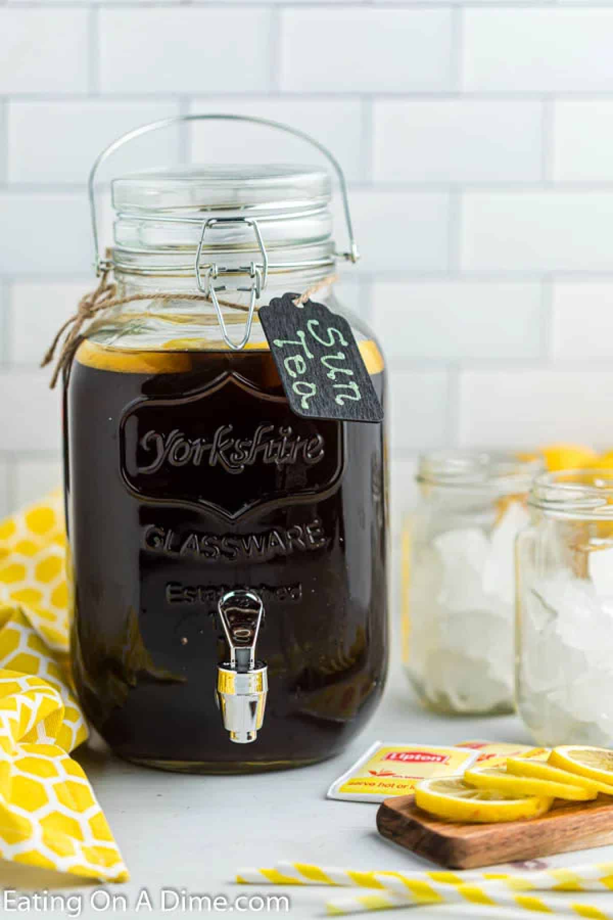 Prepared tea in a large glass picture with mason jars with ice and lemon slices on the side