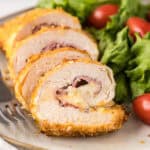 Close up image Chicken Cordon Bleu with a side salad on a plate.