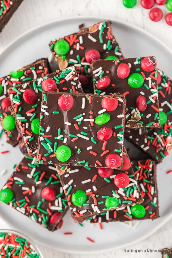 Christmas brownies decorated with red and green sprinkles and Christmas M&M stacked on a plate