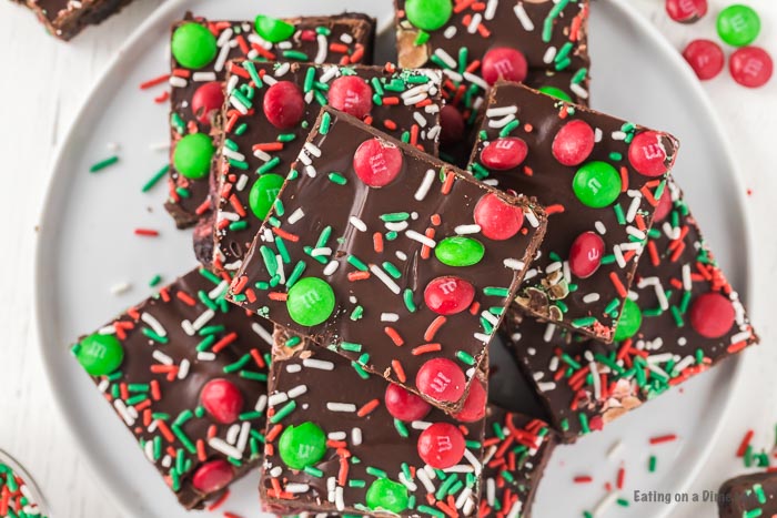 Christmas brownies decorated with red and green sprinkles and Christmas M&M stacked on a white plate