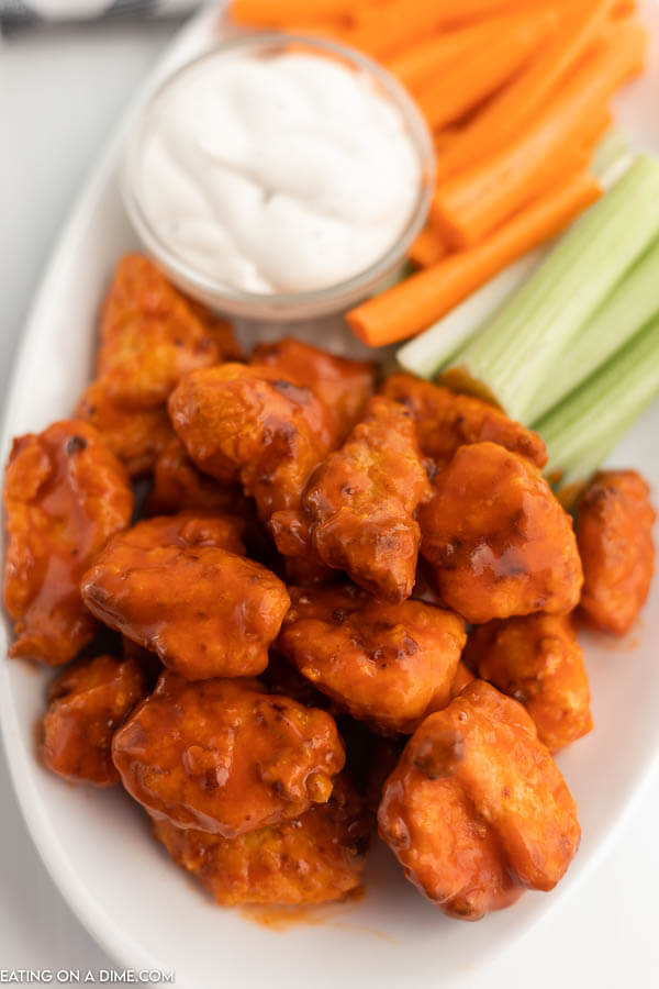 Close up image of boneless chicken wings and carrots and celery on a white plate. 
