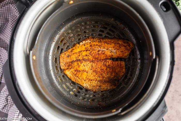 Air fryer tilapia in air fryer basket. 