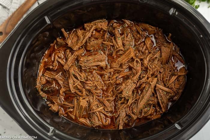 Learn how to make Crock Pot Brisket Recipe that is so tender it falls apart. The flavor from being slow cooked all day is amazing and the recipe is so easy. Close up image of shredded beef brisket in a crock pot