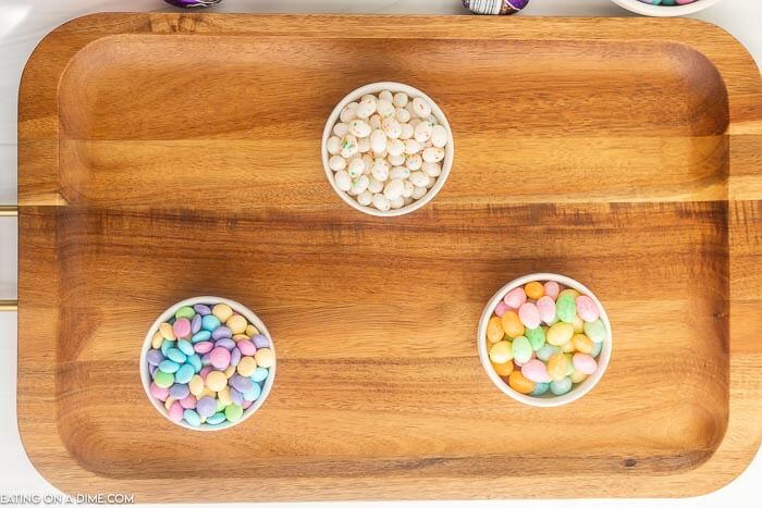 Placing the small bowls of jelly beans and M&M's on the board