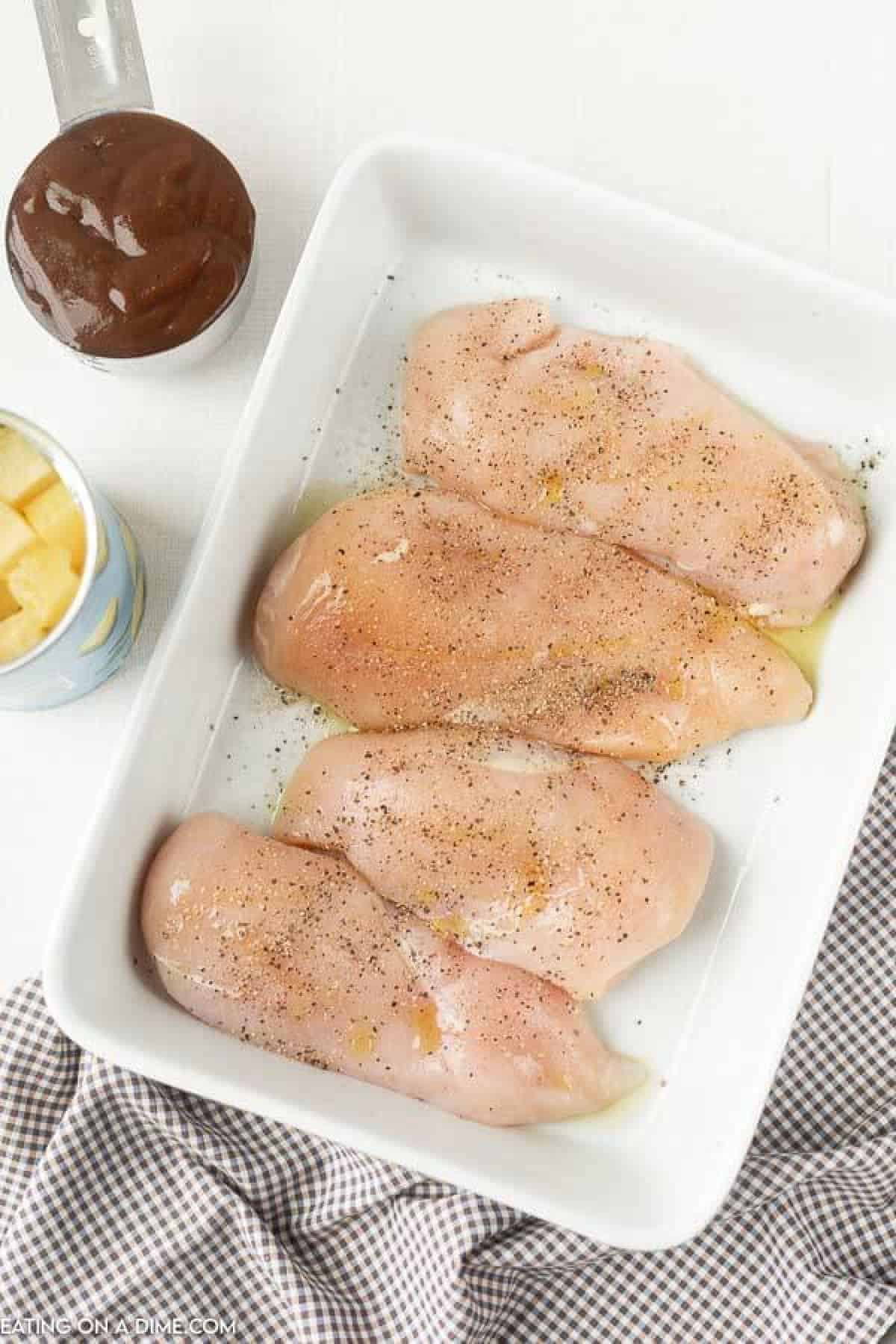 Baked Pineapple BBQ chicken recipe is the perfect meal idea and only requires 3 ingredients. It is so easy but tastes like you spent all day cooking. Chicken in a baking dish with a pineapples and BBQ sauce on the side.