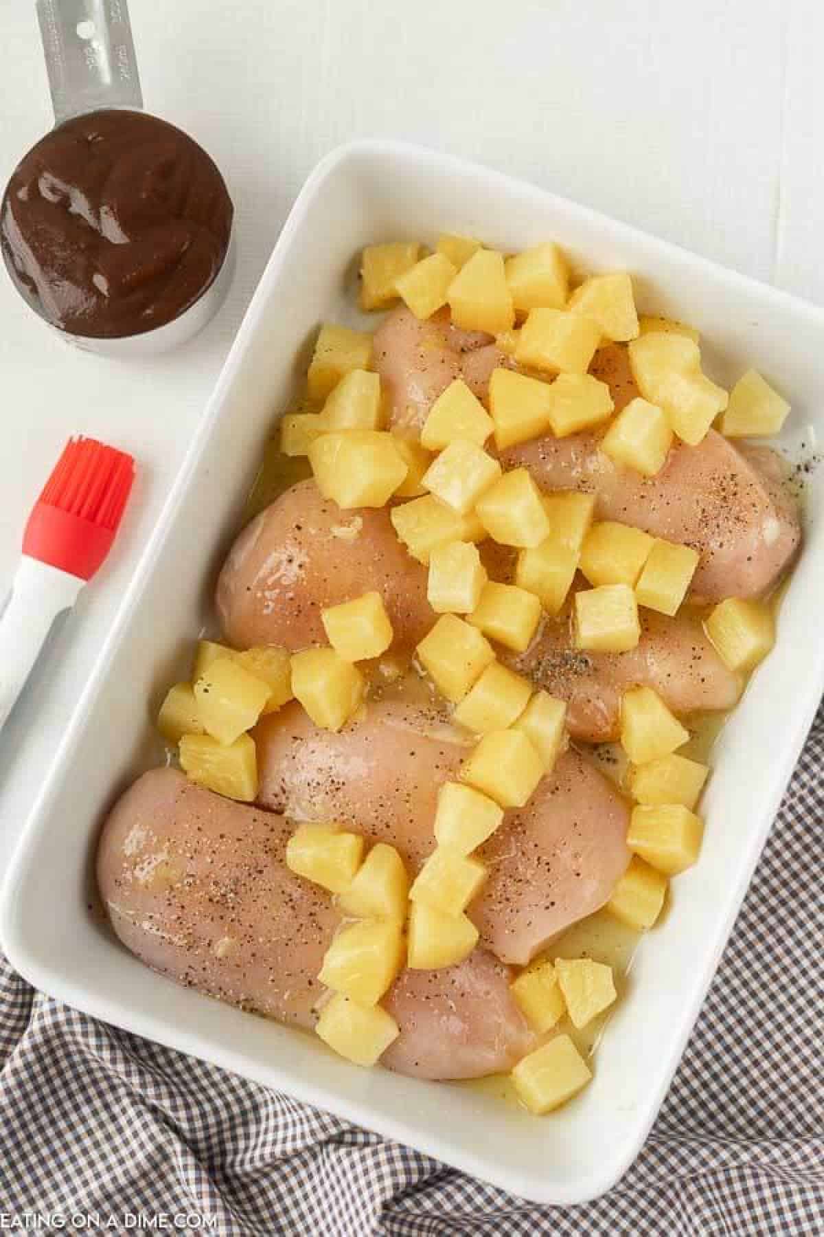 Baked Pineapple BBQ chicken recipe is the perfect meal idea and only requires 3 ingredients. It is so easy but tastes like you spent all day cooking. Chicken in a baking dish with pineapple on top.