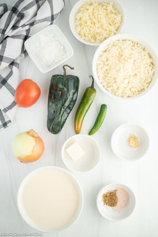 Ingredients needed - monterey jack cheese, white cheddar cheese, butter, onion, poblano pepper, serrano peppers, minced garlic, tomato, cumin, evaporated milk, cornstarch, salt