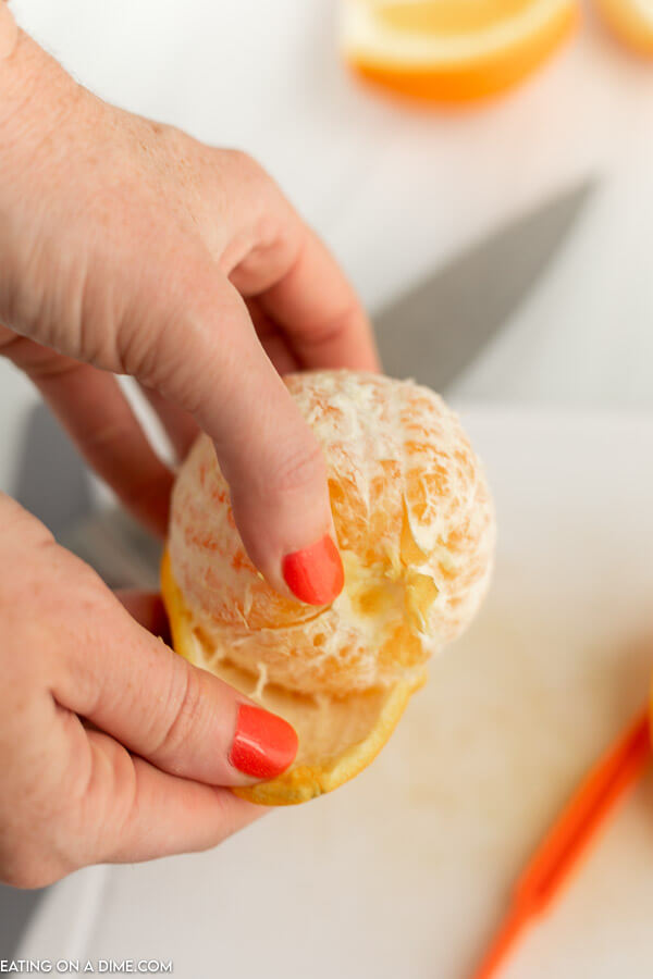 Close up image of peeling the skin from an orange. 