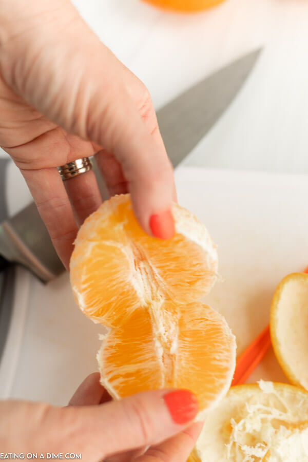 Close up image of pulling an orange apart. 